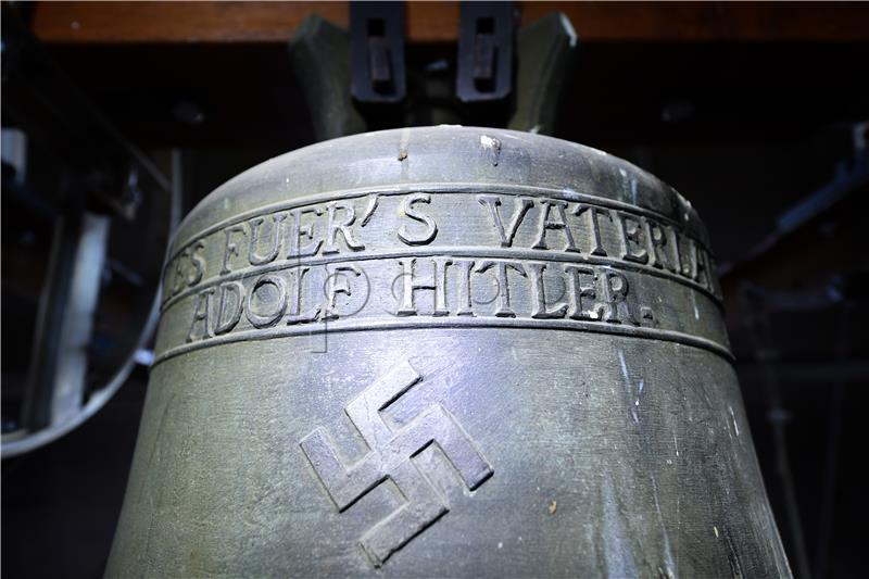 Row over bronze church bell featuring swastika